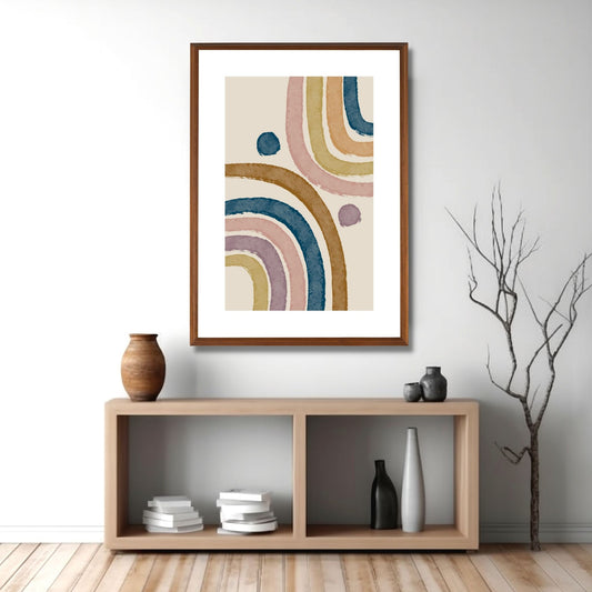 Grafisk plakat i buede linjer i brun, lilla, blå og oransje på beige bakgrunn. Plakaten har en bred hvit kant som gir dybde og fremhever motivet. Illustrasjonen viser at plakaten henger i en eikeramme på en vegg over en reol.