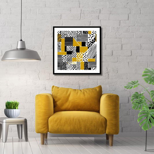 Kvadratisk plakat med abstrakt mønster i fargene oker, sort og hvit. Det er en hvit kant rundt plakaten. Her er den rammet inn i sort ramme, og henger på en hvit murvegg. Det henger en grå pendellampe og det står en gul stol under bildet.