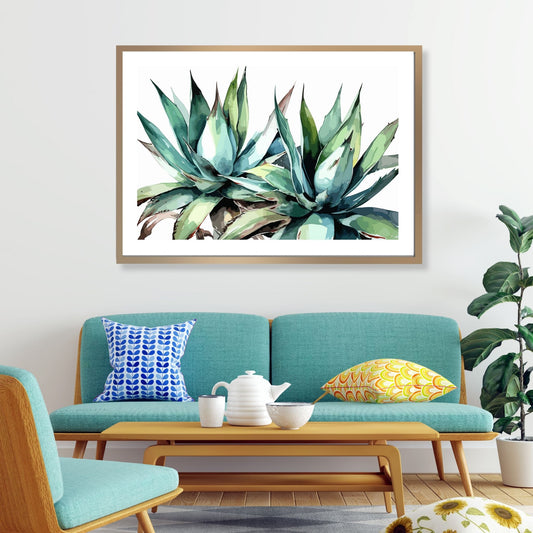 Grafisk akvarell av en praktfull Aloe Vera plante i grønne fargenyanser, mot en ren hvit bakgrunn. Illustrasjonsfoto viser motivet som plakat i en lys ramme som henger over en sofa.