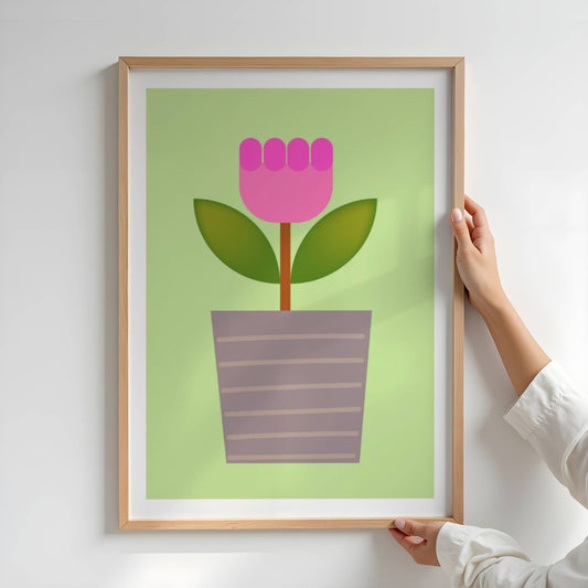 Bold Botanical No12 er en stilisert rosa blomst i to nyanser vokser opp fra en grå blomsterpotte med horisontale striper. Med dypgrønne blader og myk grønn bakgrunn stråler motivet av leken enkelhet og moderne sjarm. Illustrasjon viser plakat i eik ramme.