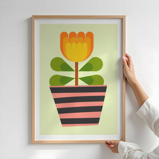 Bold Botanical No18 viser et gyllengult blomsterhode i flere lag danner blikkfanget i denne plakaten. Bladene er harmonisk arrangert i grupper med mørkegrønne hjerteformer, og alt er plantet i en potte med grafiske striper i rosa og sort. Et lekent og energisk uttrykk som avslutter serien med et stilsikkert smil. Illustrasjon viser plakat i eik ramme.