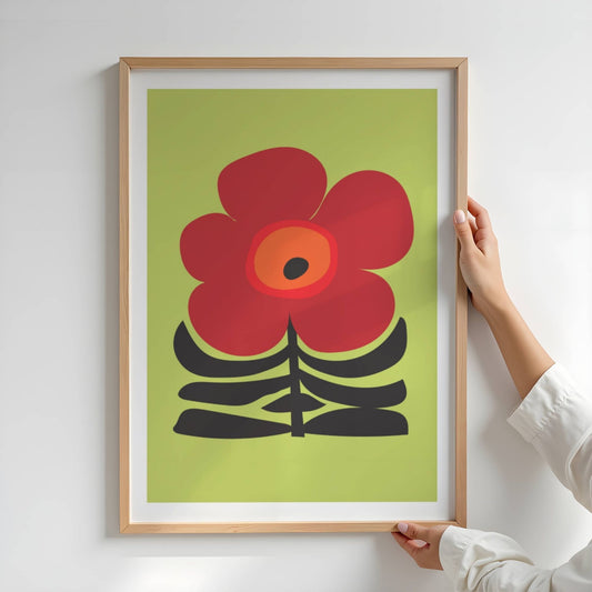 Bold Botanical No5 viser en kraftfull rød blomst med mørkt senter står i sentrum mot en limegrønn bakgrunn, med sorte, stiliserte blader som base. Det dristige formspråket og fargevalget gir plakaten en tydelig, grafisk karakter med et snev av retro. Illustrasjon viser plakat i eik ramme.