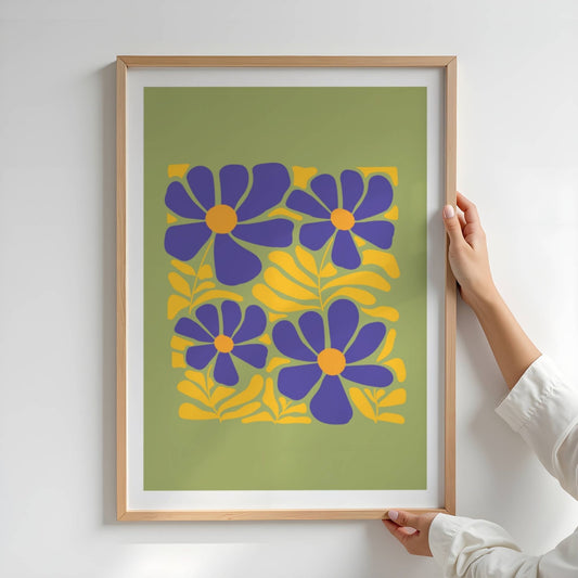 Bold Botanical No6 viser fre store blomster i dyp lilla med solgule sentre er omgitt av dekorative blader i samme varme gulfarge. Alt er satt mot en olivengrønn bakgrunn som fremhever det sterke fargespillet. Illustrasjon viser plakat i eik ramme.