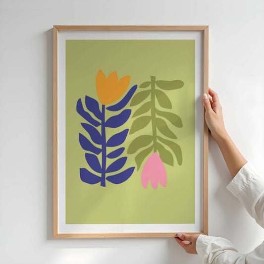 Bold Botanical No7 består av to kontrastfylte blomster stiliseres side om side – én i varme oransje og mørkeblå toner, den andre i duse grønntoner med en hengende rosa blomst. Illustrasjon viser plakat i eik ramme.