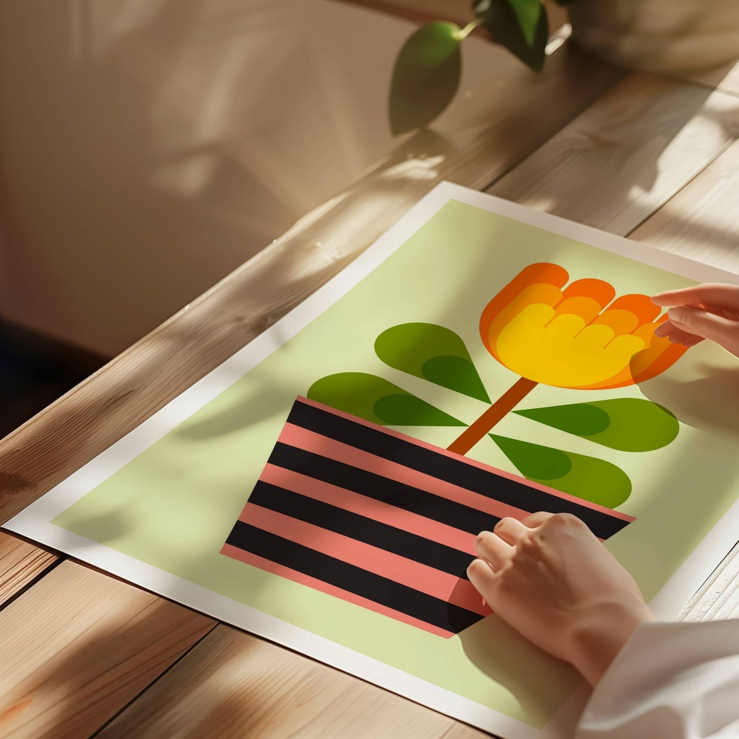 Bold Botanical No18 viser et gyllengult blomsterhode i flere lag danner blikkfanget i denne plakaten. Bladene er harmonisk arrangert i grupper med mørkegrønne hjerteformer, og alt er plantet i en potte med grafiske striper i rosa og sort. Et lekent og energisk uttrykk som avslutter serien med et stilsikkert smil. Illustrasjon viser plakat på print.