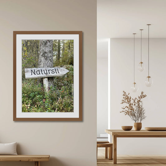 Naturlig Veiviser – Byafjellet er et sjarmerende og ekte motiv som fanger et håndlaget treskilt med teksten “Natursti”. Illustrasjon viser motivet som plakat med passepartout i brun ramme.