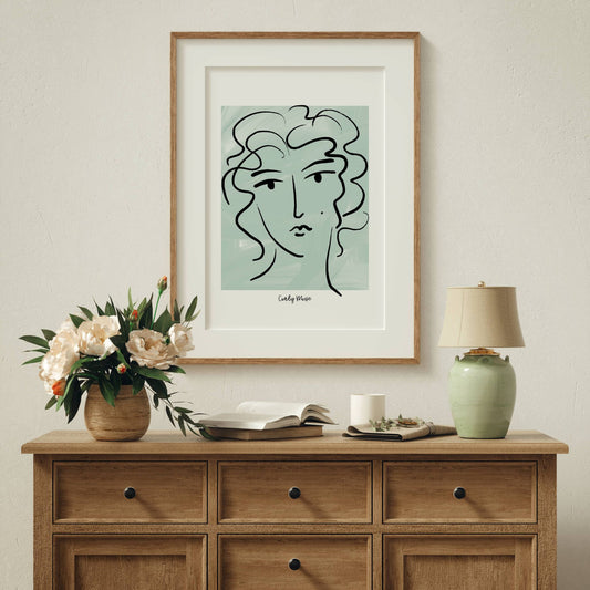 Løft rommet med en kunstnerisk vri med Curly Muse – Moderne Portrettplakat. Illustrasjon viser plakat med passepartout i eik ramme.