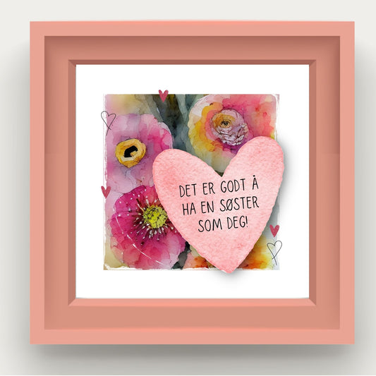 Grafisk plakat med et rosa hjerte påført tekst "Det er godt å ha en søster som deg". Bagrunn i cerise og guloransje blomster. Illustrasjonen viser plakat i rosa ramme.