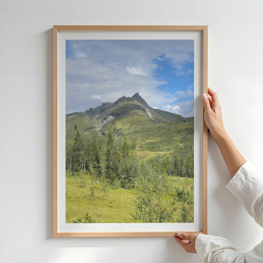 Dærga – i Røyrvik er et majestetisk motiv av fjelltoppen Jillie Daerka (1108 moh), sett fra et åpent fjellandskap med frodige grøntoner og dramatisk himmel. Illustrasjon viser motivet som plakat med hvit kant i eik ramme.