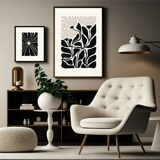 Bildet viser en grafisk plakat i abstrakt, floralt mønster i sort, beige og dempet hvit bakgrunn. Plakaten har en bredt kant i dempet hvit farge rundt og henger i sort ramme på en lys brun vegg.