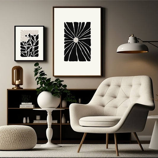 Miljøbilde som viser en grafisk plakat i abstrakt, floralt mønster i sort, beige og dempet hvit bakgrunn. Plakaten har et bredt felt rundt i bakgrunnsfarge, og henger i sort ramme på en lys brun vegg