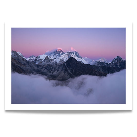 Dette fantastiske bildet viser Mount Everest, dekket av snø og innhyllet i tåkedekte skyer under en vakker, rosa-lilla skumringshimmel.