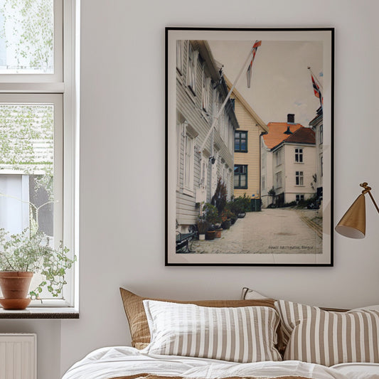 Gamle Nøstegaten på Sydnes byr på en rolig og stemningsfull atmosfære, med sine smale gater og karakteristiske trehus. Illustrasjon viser plakat i sort ramme.