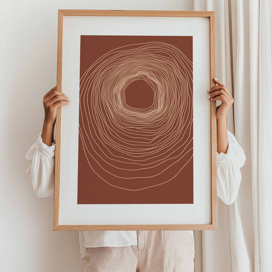 "Harmoniens Kjerne" er en minimalistisk plakat inspirert av naturens organiske vekst. De sirkulære linjene gir en hypnotisk dybde, som minner om årringene i et tre eller energisirkler i naturen. Illustrasjo viser plakat i eik ramme.