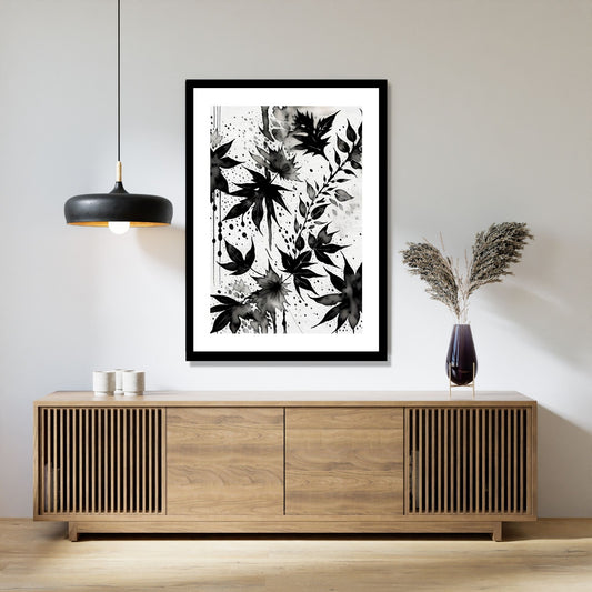 Miljøbildet viser en grafisk plakat i abstrakt, floralt mønster i sort-hvitt. Plakaten som har en dekorativ hvit kant, henger i en sort ramme over en skjenk i teak. Ved siden henger en sort lampe og på skjenken står det en sort vase med strå.