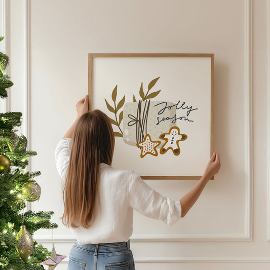 Et søtt og nostalgisk motiv med teksten Jolly Season, pyntet med pepperkakefigur og gave i myke naturfarger. Illustrasjon viser plakat i eik ramme.
