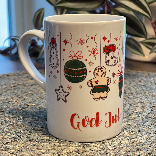 Hvitt krus i keramikk med håndtak. Kruset er påført et håndtegnet julemotiv og God Jul. Volum: 29 cl. Diameter: 7 cm. Høyde: 10,5 cm.