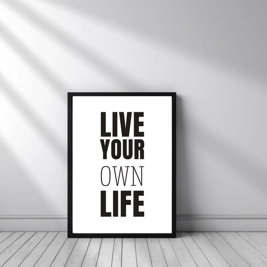 Grafisk plakat med sort skrift på hvit bakgrunn. Tekst på plakat "Live your own life" Illustrasjon viser plakat i sort ramme.