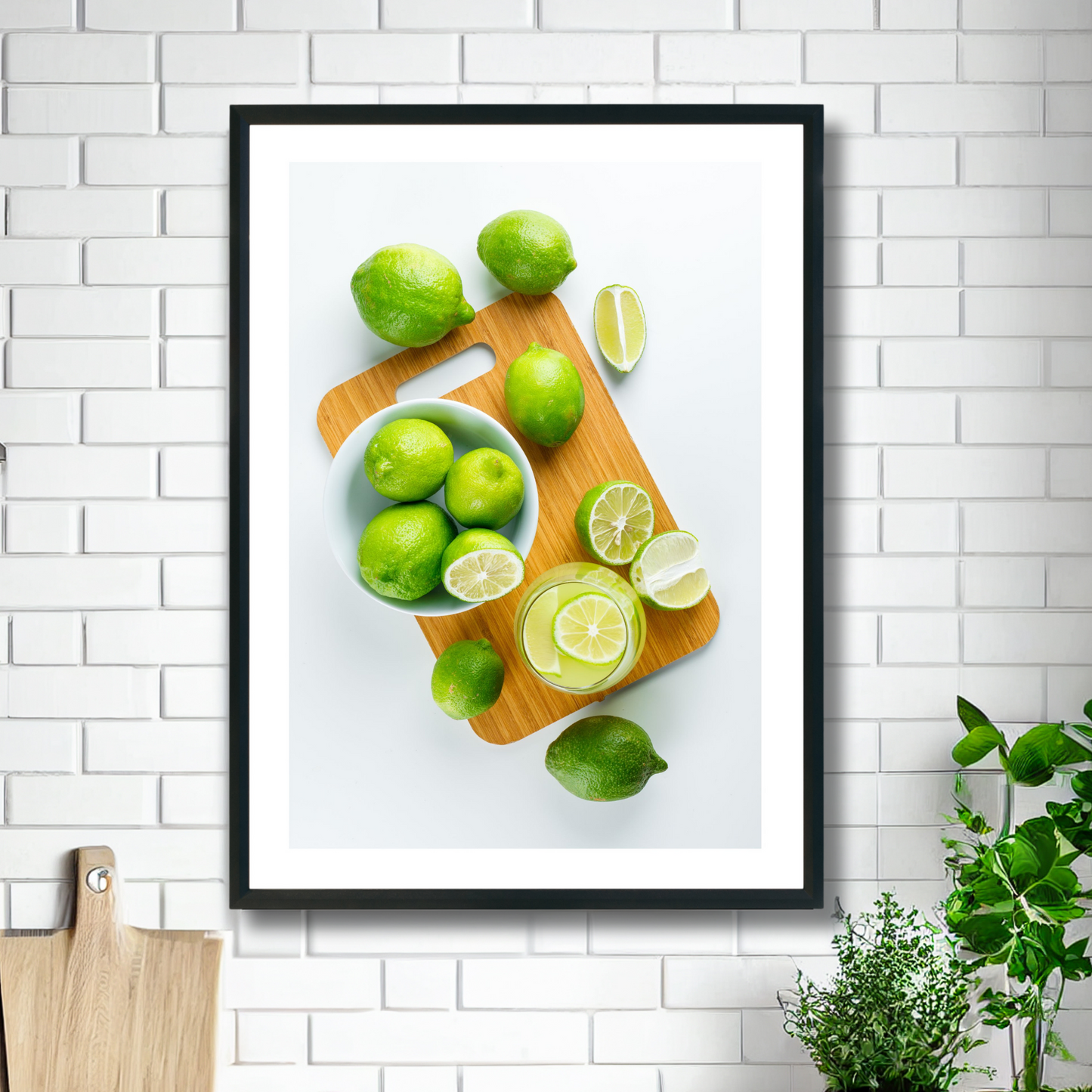 Fotoplakat med motiv av lime , i skiver og i et glass med drikke. Illustrasjonsbilde viser plakat i sort ramme som henger på en vegg over.