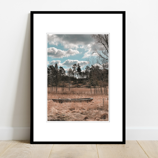 Pram har gått på land ved Spetalen. Foto av en pram som ligger i engen i fine omgivelser med furutrær og himmel med spektakulære skyer.