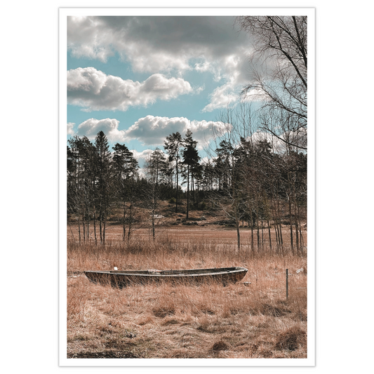 Pram har gått på land ved Spetalen. Foto av en pram som ligger i engen i fine omgivelser med furutrær og himmel med spektakulære skyer.