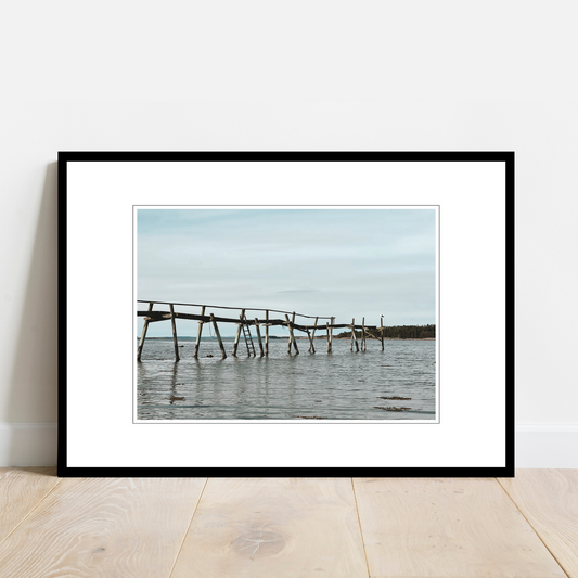 Gammel brygge, strandkant, sjø og hvite skyer ved Saltnes. Vakkert norsk kystlandskap i Østfold som vil være dekorativ på en fotoplakat.