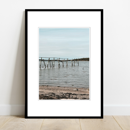 Gammel brygge, strandkant, sjø og hvite skyer ved Saltnes. Vakkert norsk kystlandskap i Østfold som vil være dekorativ på en fotoplakat.