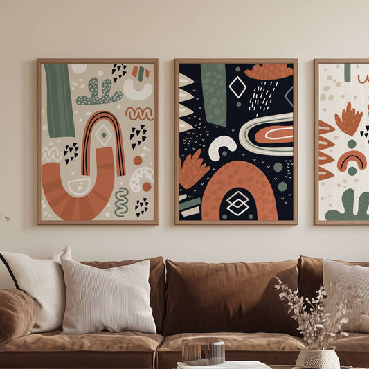 Nordic Abstractions Collection – 3 grafiske plakater. Illustrasjon viser plakatserien uten hvit kantlinje i rammer av eik på en vegg over en sofa.