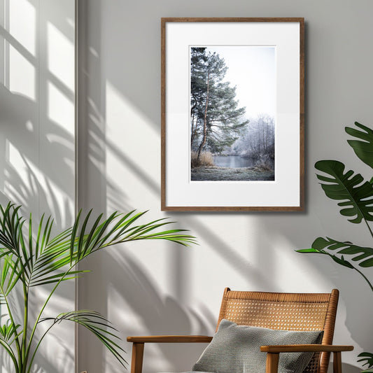 Dette motivet fanger essensen av et stille, vinterlig landskap, med snødekte trær ved en islagt innsjø. Illustrasjonsfoto viser motiv i mørk ramme med passepartout.