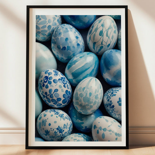 Dette elegante motivet viser en samling håndmalte påskeegg i ulike blåtoner, dekorert med delikate mønstre inspirert av akvarellkunst. Illustrasjon viser plakat i sort ramme.