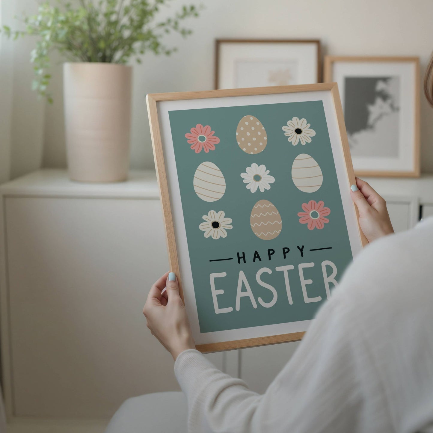 Denne dekorative påskeplakaten kombinerer vakre pastellfarger, stilrene påskeegg og delikate blomstermotiver for å gi hjemmet ditt en varm og livlig påskefeiring. Illustrasjon viser plakat med hvit kant i eik ramme.