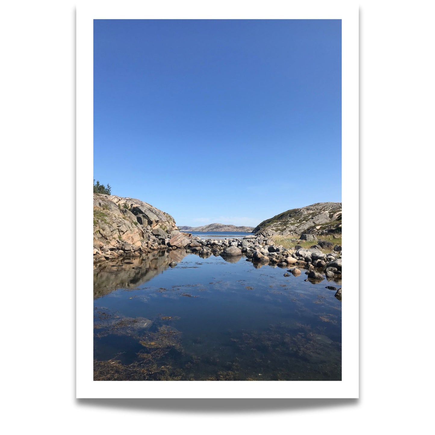 Mellom to klippeformasjoner åpner landskapet seg mot hav og øyer. Dette er et motiv for deg som søker ro, klarhet og den stille storheten som bare norsk kystnatur kan gi.