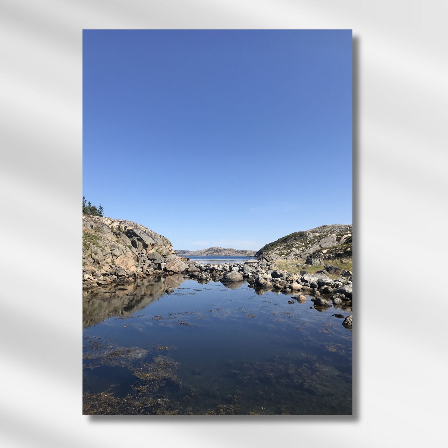 Mellom to klippeformasjoner åpner landskapet seg mot hav og øyer. Dette er et motiv for deg som søker ro, klarhet og den stille storheten som bare norsk kystnatur kan gi. Illustrasjon viser motivet på lerret.