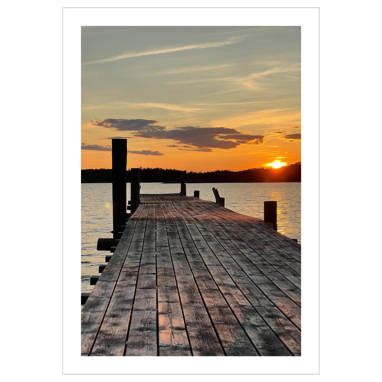 Nydelig solnedgang ved Krokstadfjorden ved Saltnes. Motiv av en brygge som går ute i sjøen, og en sol som er i ferd med å gå ned på en oransje himmel. Fås både som plakat og på lerret.