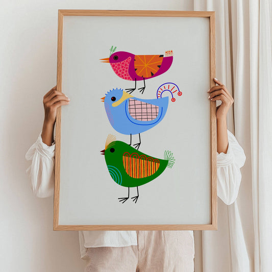 Syngende Fugler – Plakat viser tre fantasifulle fugler i duse, men lekne farger stablet på hverandre som et kor klart til å synge våren inn. En perfekt kombinasjon av grafisk design og barnlig sjarm. Illustrasjon viser plakat i eik ramme.