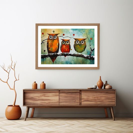 Abstrakt motiv av tre fargerike ugler som sitter på en gren. Illustrasjonsbildet viser motivet som plakat med passepartout i en eikeramme, som henger på en vegg over en sjenk.