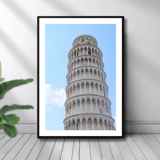Dette motivet fremhever de elegante buene og detaljene i det ikoniske skjeve tårnet i Pisa, sett mot en klar himmel. Illustrasjon viser motivet som plakat i sort ramme.