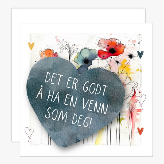 Kort med blått hjerte med tekst "Det er godt å ha en venn som deg" og bakgrunn med fargerik blomstereng. Konvolutt er inkludert.