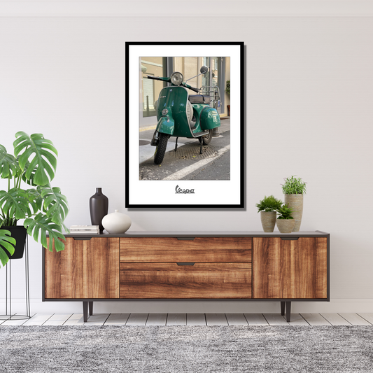 Fotografi av en grønn Vespa parkert foran en bygning i en gate i Italia. Plakaten har en hvit kant.