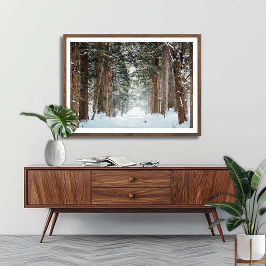 Denne plakaten og lerretet fanger en stemningsfull vintersti omringet av majestetiske, snødekte trær som strekker seg høyt mot himmelen. Illustrasjonsfoto viser motivet som plakat i brun ramme.