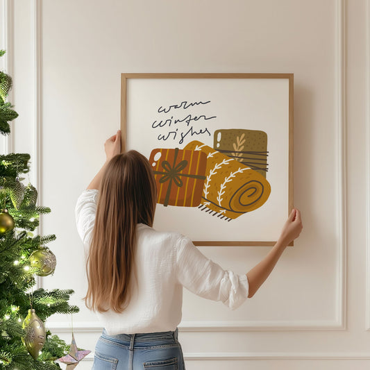 Et harmonisk motiv med teksten Warm Winter Wishes, hvor gaver og et sammenrullet pledd skaper en følelse av komfort og ro. Illustrasjon viser plakat i eik ramme.