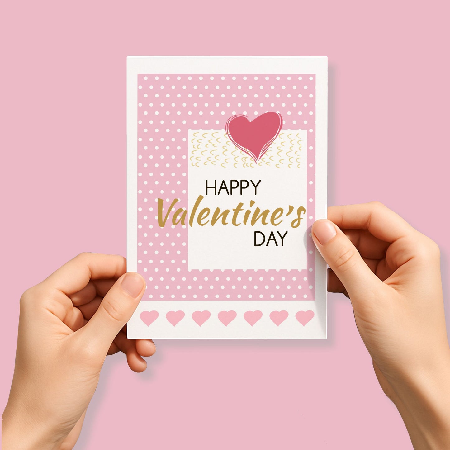 Kjærlighetskort med teksten Happy Valentine’s Day, grafisk rosa hjerte, prikket bakgrunn og dekorative detaljer i myke rosatoner. Person som holder kort.