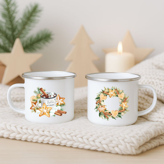 Hvitt emaljekrus med to julemotiver: vinterkakao med pepperkaker og en pepperkakekrans, fotografert på lys strikket duk med juledekor i bakgrunnen.