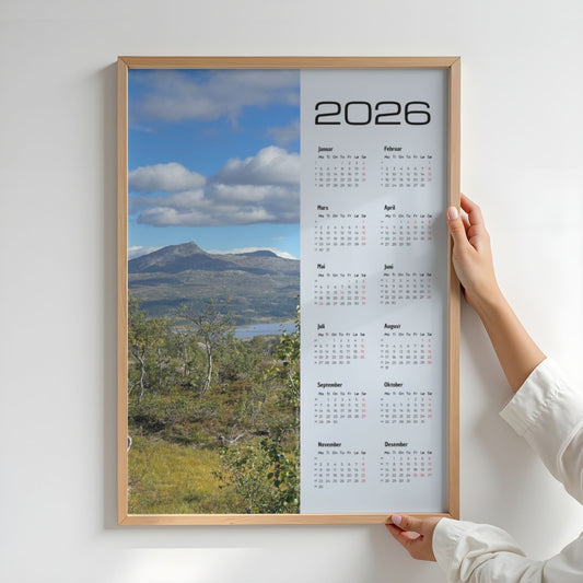 Kalender 2026 med foto av Dærgafjellet i Røyrvik, sett over fjellterreng og høstlig vegetasjon. Illustrasjon viser kalender i eik ramme.