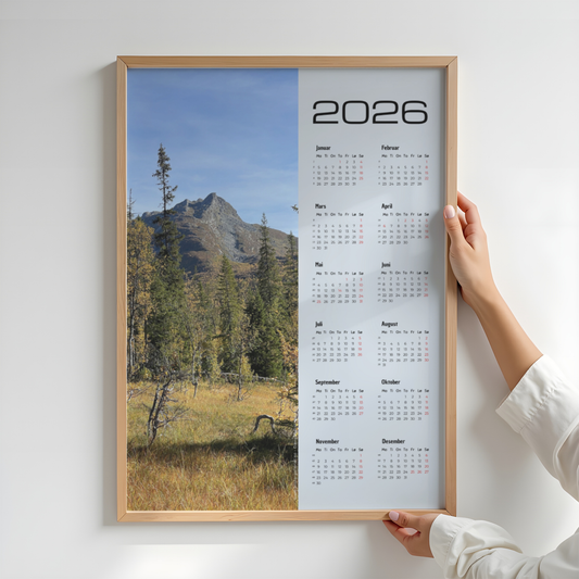 Kalender 2026 med foto av høstskog og fjell ved Dærgafjellet i Røyrvik. Illustrasjon viser kalender i eik ramme.