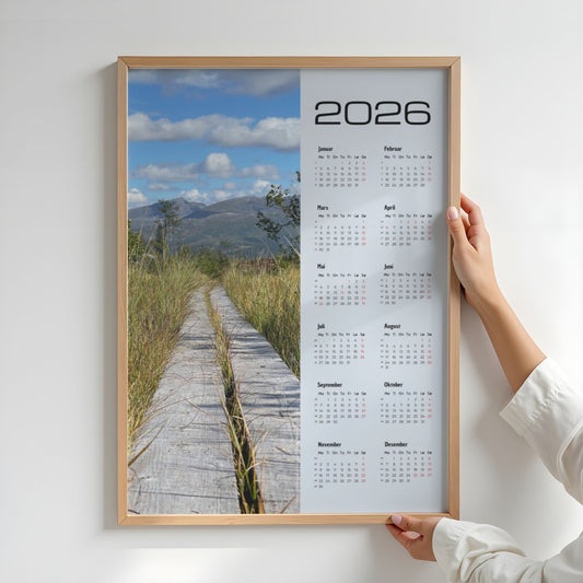Kalender 2026 med foto av en plankesti som leder inn i fjellandskapet. Illustrasjon viser kalender i eik ramme.