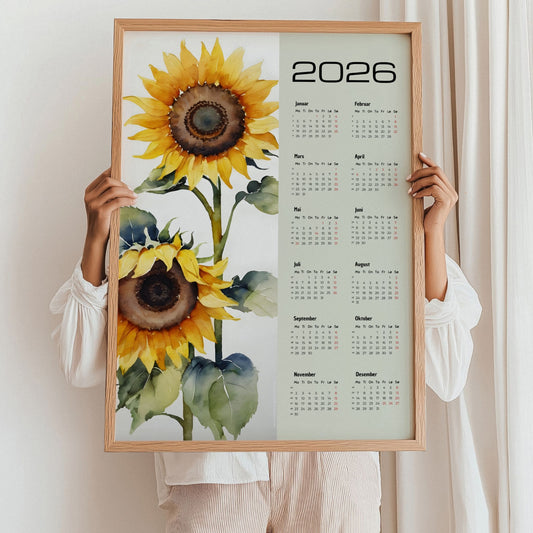 Kalender 2026 med store solsikker i akvarellstil ved siden av årskalender. Illustrasjon viser kalender i eik ramme.