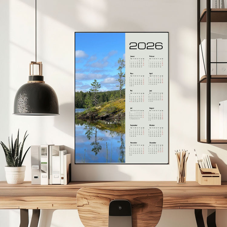 Fotokalender 2026 i ramme med norsk naturmotiv, hengende over skrivebord i lyst og moderne interiør.