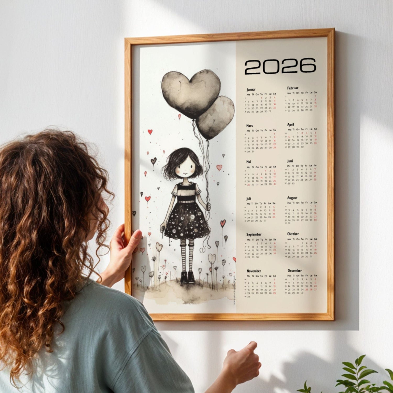 Illustrert kalender 2026 i ramme med kunstnerisk motiv, brukt som veggdekor i hjem med naturlig lys.