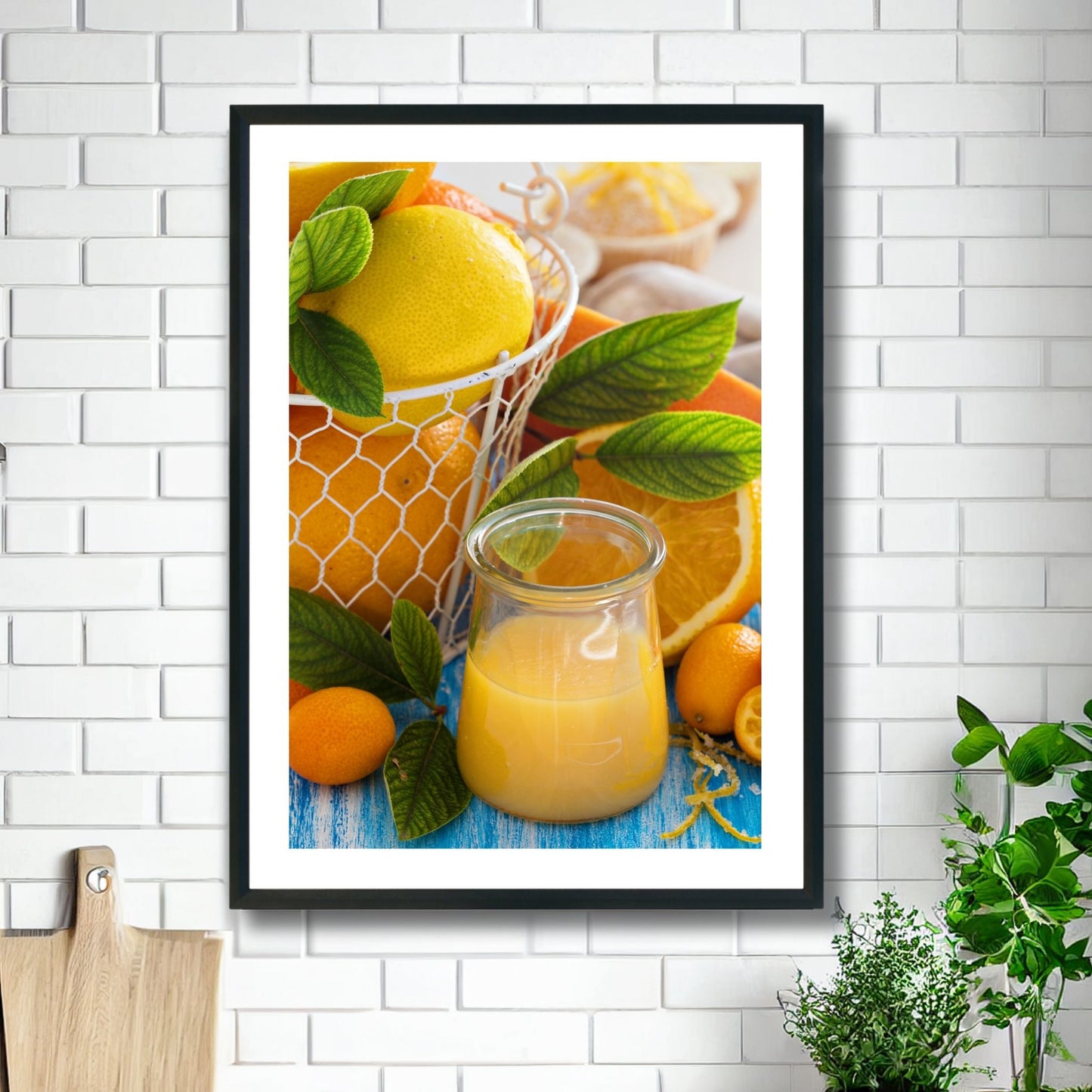 Fotoplakat av appelsiner og et glass med juice. Illustrasjonsvilde viser plakat i sort ramme på et kjøkken.